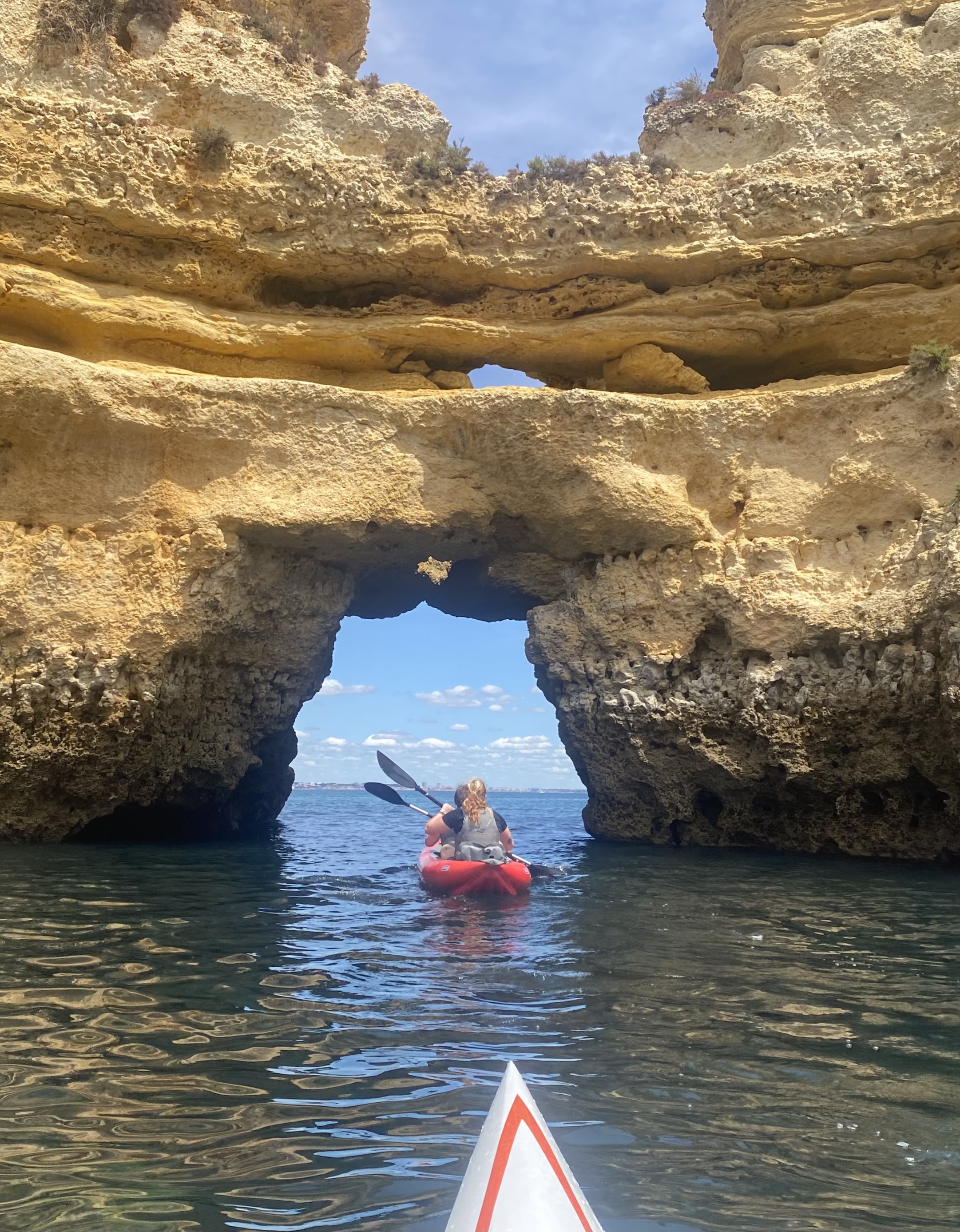 Kayaks going under sea arch